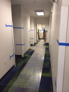 A photograph of an office hallway with protective plastic on the carpet